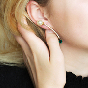 model wearing a curving earring with pearl and emerald crystal