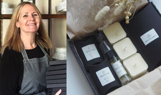 Founder of Wild Planet Aromatherapy holding black letterbox gifts in her studio in Kent with a Hug In A Box Letterbox Gift and dried flowers