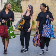 3 women carrying lots of colourful african print tote bags