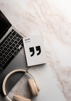Front cover of the lyric book on marble background with Beats headphones and laptop 