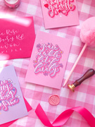 Colourful calligraphy greeting cards on a pink gingham background