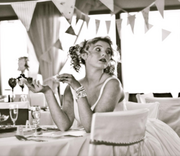 bride sitting at a table with bunting draped in the background