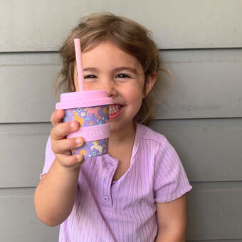 Girl holding unicorn babyccino cup with straw