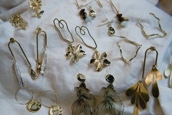 Flat lay of different gold jewellery designs on white linen sheet