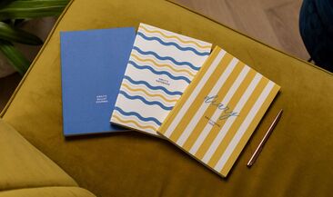 3 personalised planner covers laid out on a couch.