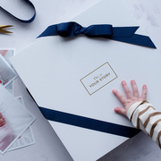 A child's hand resting on our baby record book gift box