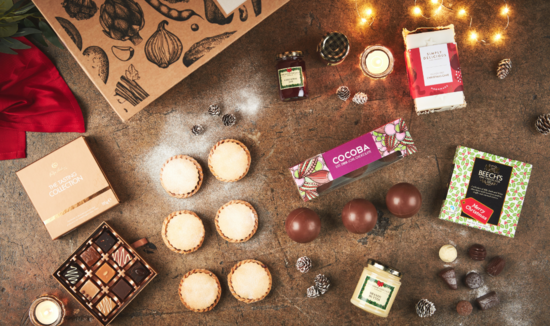 A festive image of mince pies, hot chocolate, sweet treats and icing sugar with fairy lights and Christmas decorations