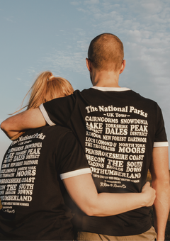 a couple wearing a black ringer t-shirt with the uk national parks print on the back