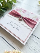 Mother's Day Greetings Card. White Square Card with Dusky Pink Border. Floral paper with decorative lace and ribbon with a heart shaped charm.