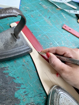 Dog collar pattern on leather being cut out by a hand with scalpel 