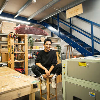 Owner, Nihal Shah sitting on a bar stool in his studio workshop