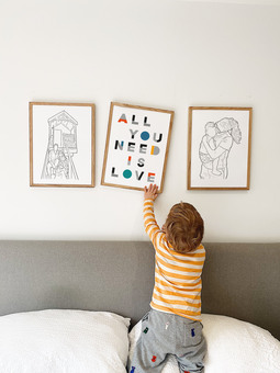 A collection of bespoke illustrations, family portraits and typography prints arranged on the bedroom wall by la Fam Illustration.