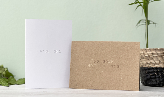 A white braille card with thank you written is next to a kraft brown card with on your wedding day.