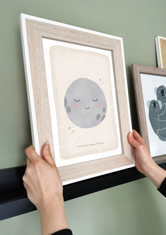 Moon print in a frame being placed on a shelf