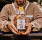 Beekeeper Andre Cardona holding a bottle of Hitchin Honey Gin, made using honey from our own Hertfordshire beehives