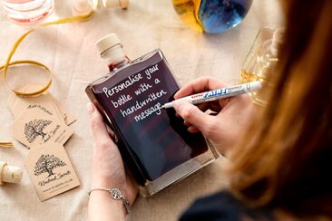 a handwritten message is being added to a bottle of craft spirits
