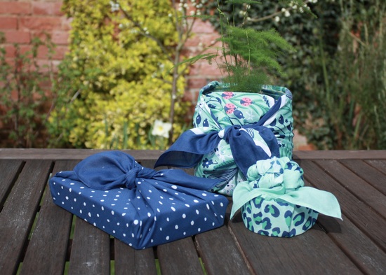 Selection of gifts wrapped in furoshiki fabric wraps in mint green and navy patterns