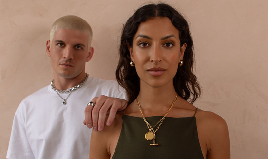 Male & female wearing necklaces & earrings from The 8th jewellery brand