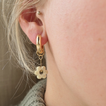 Flower charm hoop earrings in an ear