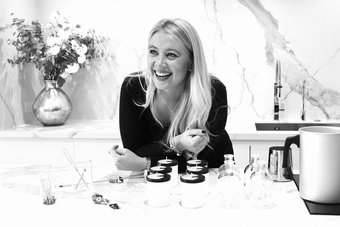 Image of founder, Alice smiling into the camera with THE ZEN HUB candle in front of THE ZEN HUB candles 