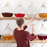 a man is decanting craft spirits into a bottle from a demijohn