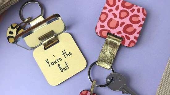 lady in teal trousers gifting another lady a pink floral keyring