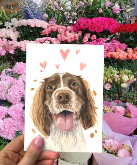 Our Licks and Kisses Spaniel Card for Valentines and Anniversaries, held up in front of a flower display