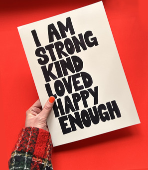 Hand holding typography print with positive affirmations on a red background