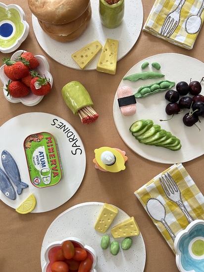 A table setting of various handmade ceramic platters inspired by food