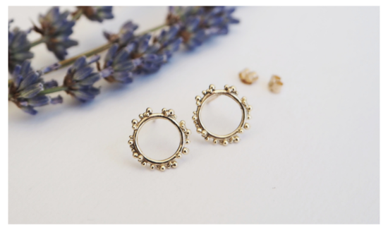 Recycled gold circle studs decorated with tiny gold spheres, studs sit on a white background decorated with british lavender.