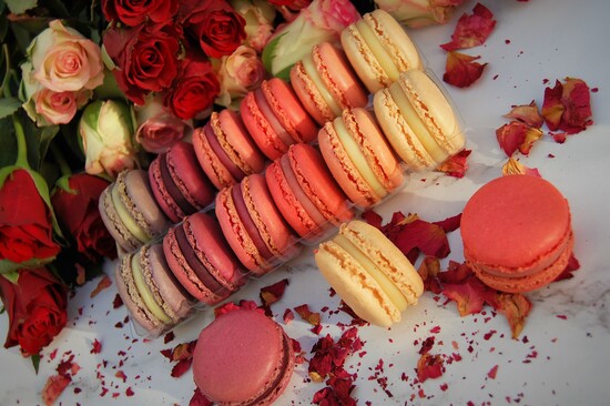 Red, pink and white macarons surrounded by roses.