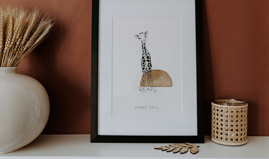 Polly Pickle giraffe stand tall print, framed in a terracotta lifestyle setting 