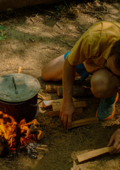 person cooking over fire on foraging course