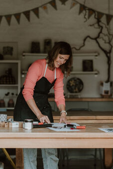 Image of Kirsty Hall making inking up a print block. 