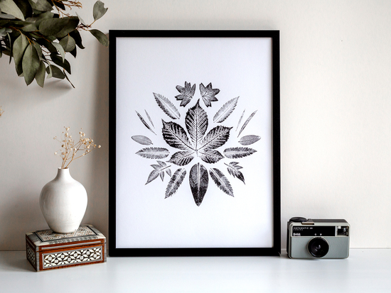 a mixed leaf monochrome botanical print in a black frame styled lifestyle photo