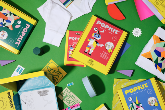 This is an arrange ment of popkit boxes, different wooden shapes, stickers and clothing showing the designs. 