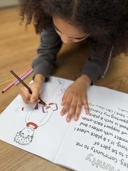 Girl lying on the floor colouring in a child in a colouring book