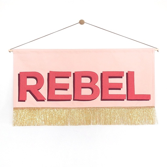 Pink banner with the word REBEL in 2 shades of red and gold tassles