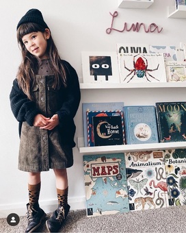 Luna with her custom name sign for her bedroom above her bookcase