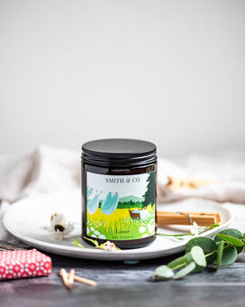 A soy candle with a fresh clean cotton fragrance. It is illustrated with a clothes line in a grassy field. 