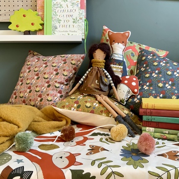 Wildflower rag doll and fox cushion sitting with woodland cushions and play mat.