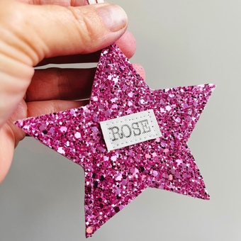 A personalised glitter star decoration with the name Rose sewn on to it.