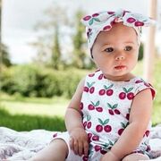 A baby girl wearing zac and bella cherries romper and headband