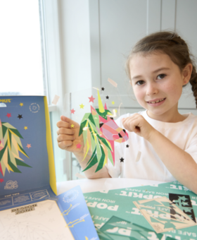 This image shows a young girl proudly holding up her POPKIT design of a unicorn.