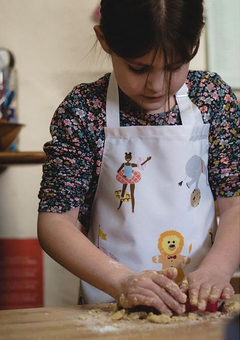 Young girl baking in the kitchen wearing a Hele Jelly Bean apron.