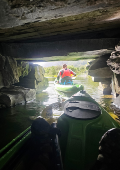 A Kayaker paddles under a tunnel on llyn padarn lake in north wales as part of a guided kayak tour with paradise adventures. the kayaks are green
