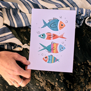 A hand holding a print showing four fish blowing bubbles