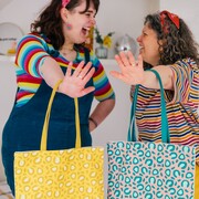 Lady in a stripy top holding out a colourful motivational card with a rainbow