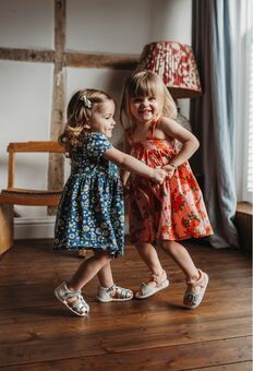 Two little girls dancing in a room wearing Pip and Henry sandals.