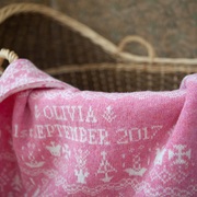 pink baby blanket draped over baby basket